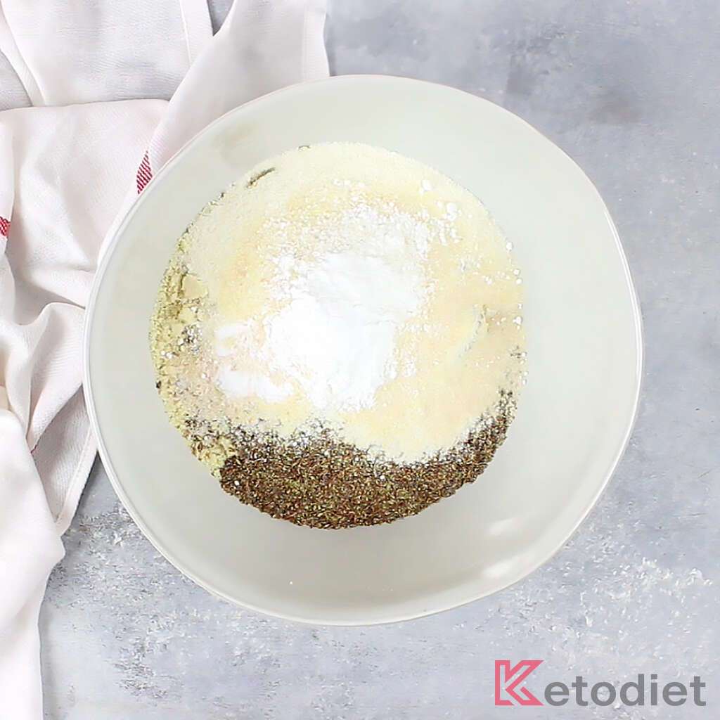 Mixing dry bread ingredients: almond flour, coconut flour, flax meal, psyllium husks, seasoning, baking powder and salt.